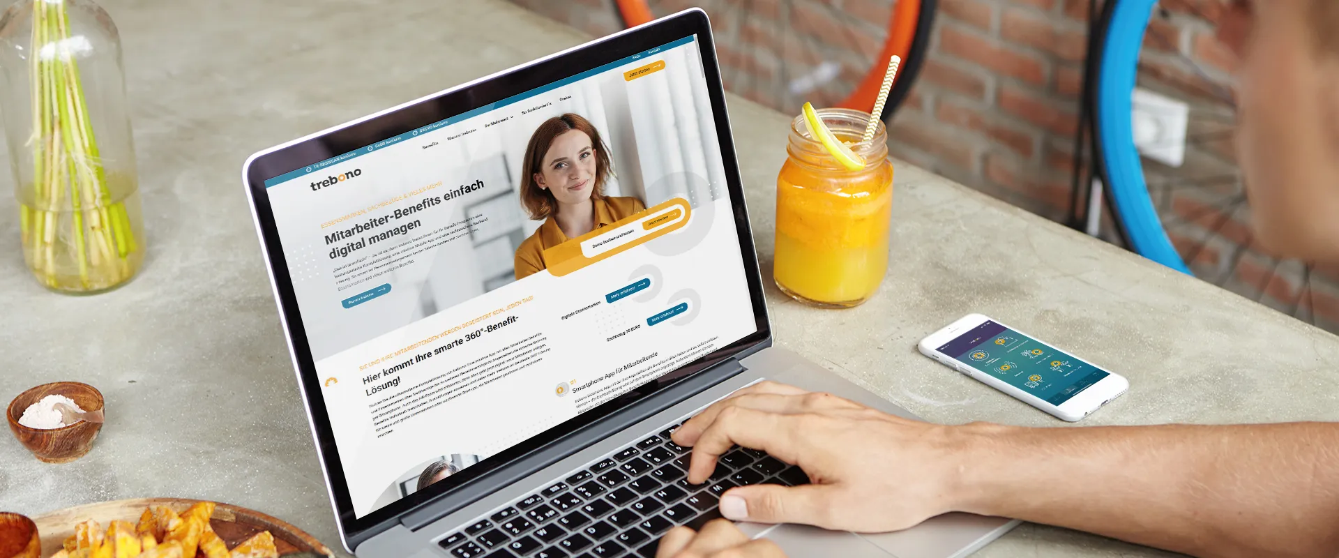 Website-Relaunch mit CMS WordPress - Ein Mann schaut auf einem Lapptop die Startseite mit den Mitarbeiter-Benefits und trebono-App auf Smartphone an