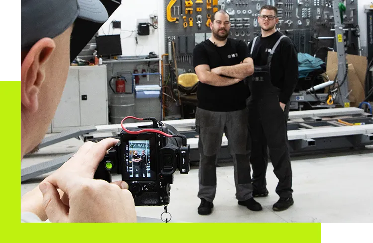 Paid Social - Fotograf nimmt in einer Werkstatt zwei Mitarbeiter in Arbeitskleidung für professionelle Social-Media- oder Employer-Branding-Fotos auf