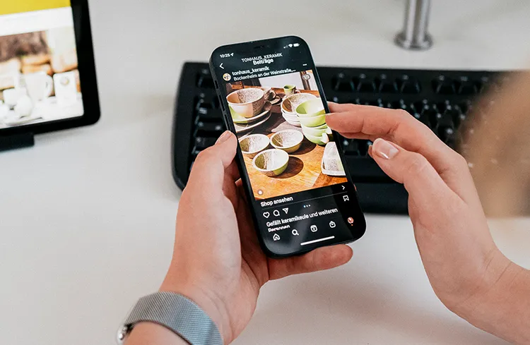 Social Advertising - Hand hält Smartphone mit Social-Media-Anzeige während der Optimierung einer Werbekampagne im Online-Marketing